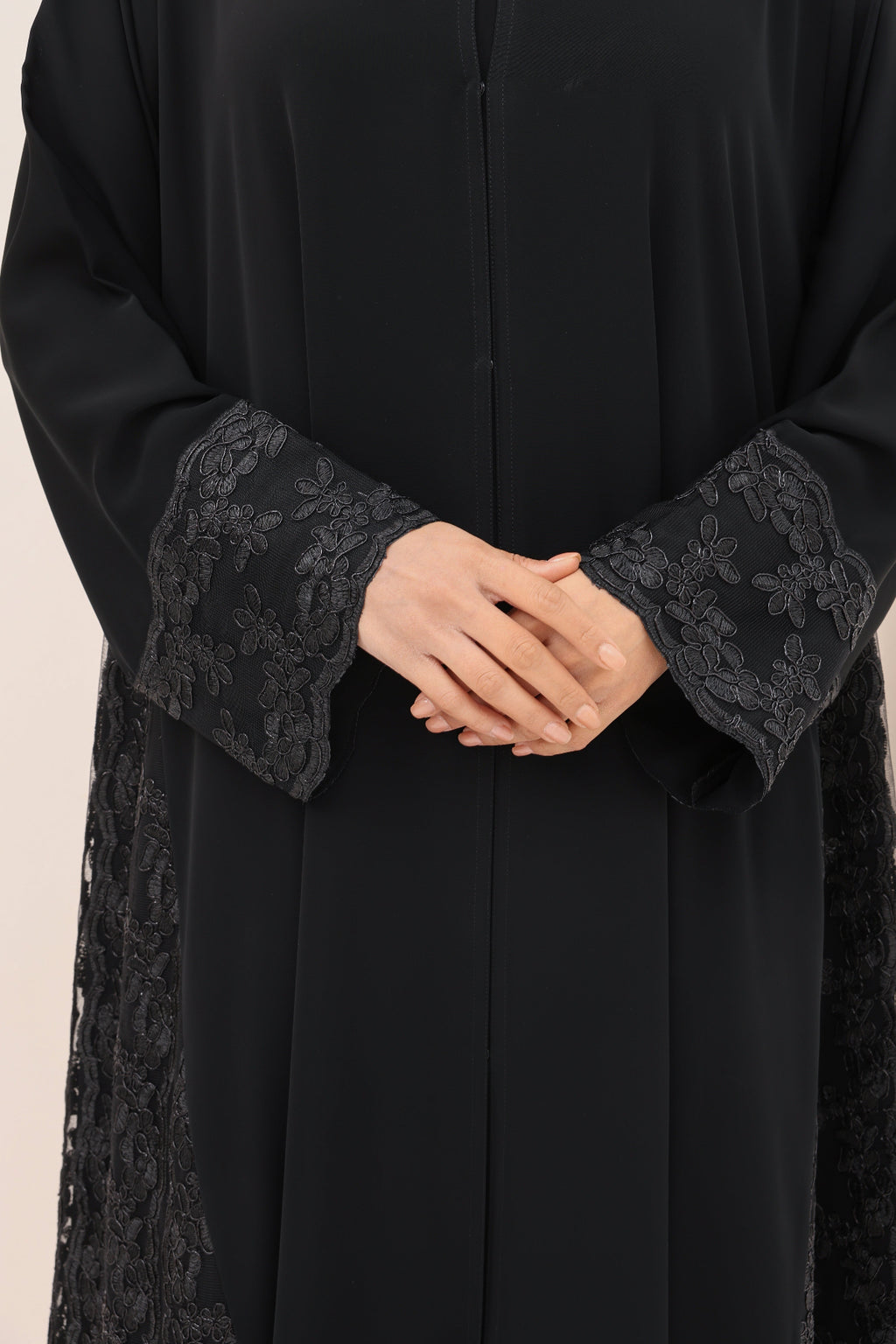 Black abaya with lace cuffs on a beige background