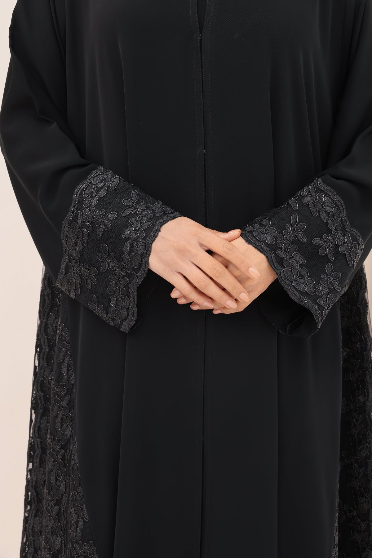 Black abaya with lace cuffs on a beige background