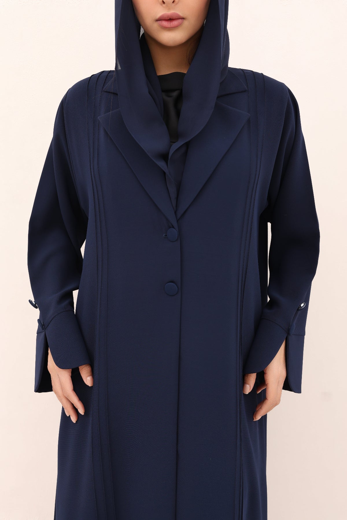 Navy blue hooded coat worn by a person on a beige background