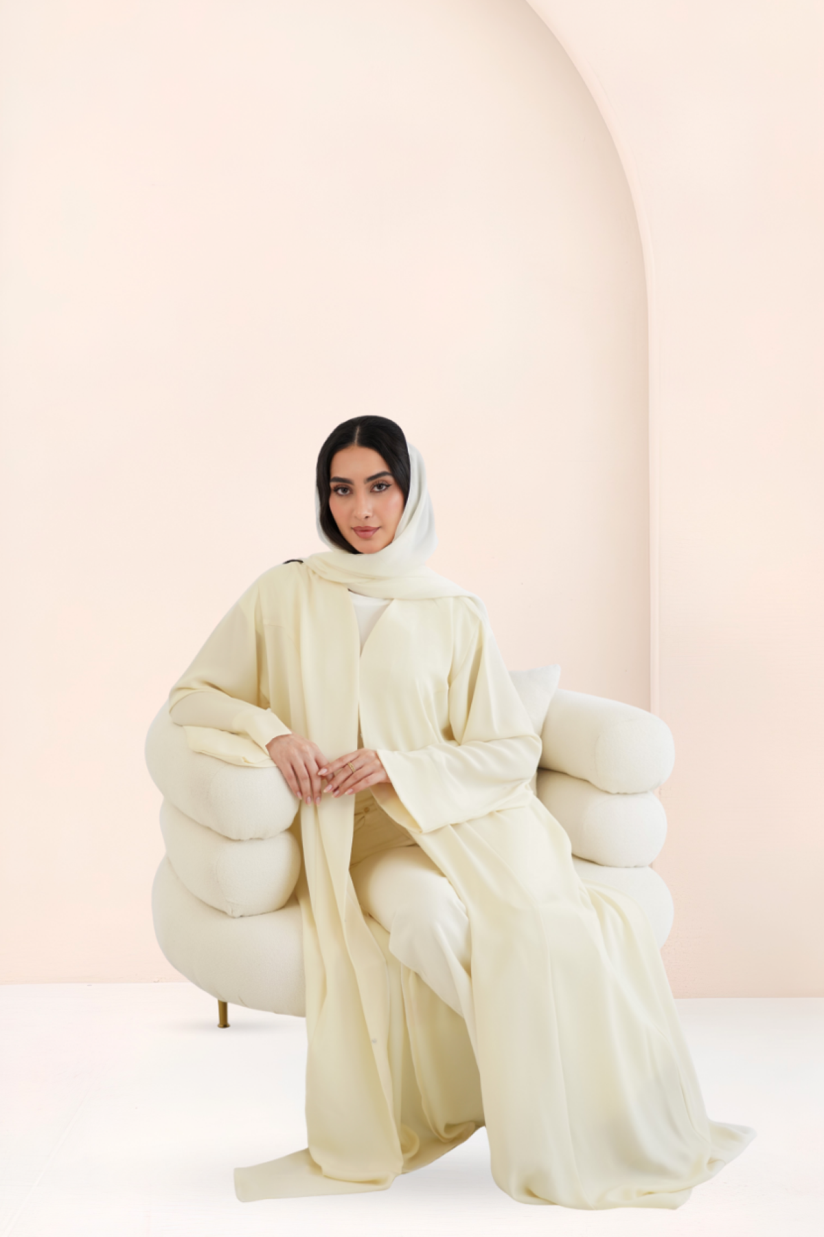 Model seated wearing Riwa Mango Smoothie abaya set with straight sleeves
