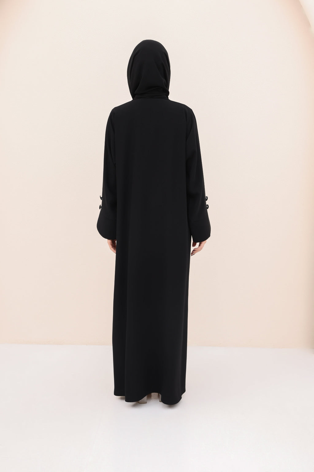 Black abaya worn by a person on a white background