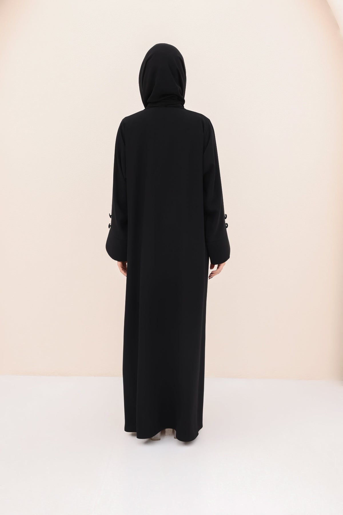 Black abaya worn by a person on a white background