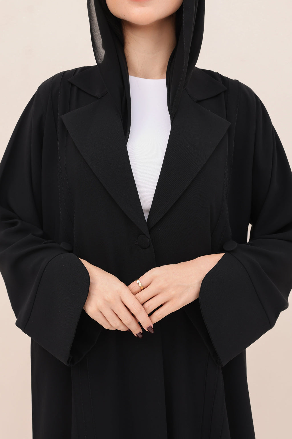 Person wearing a black coat over a white shirt on a beige background