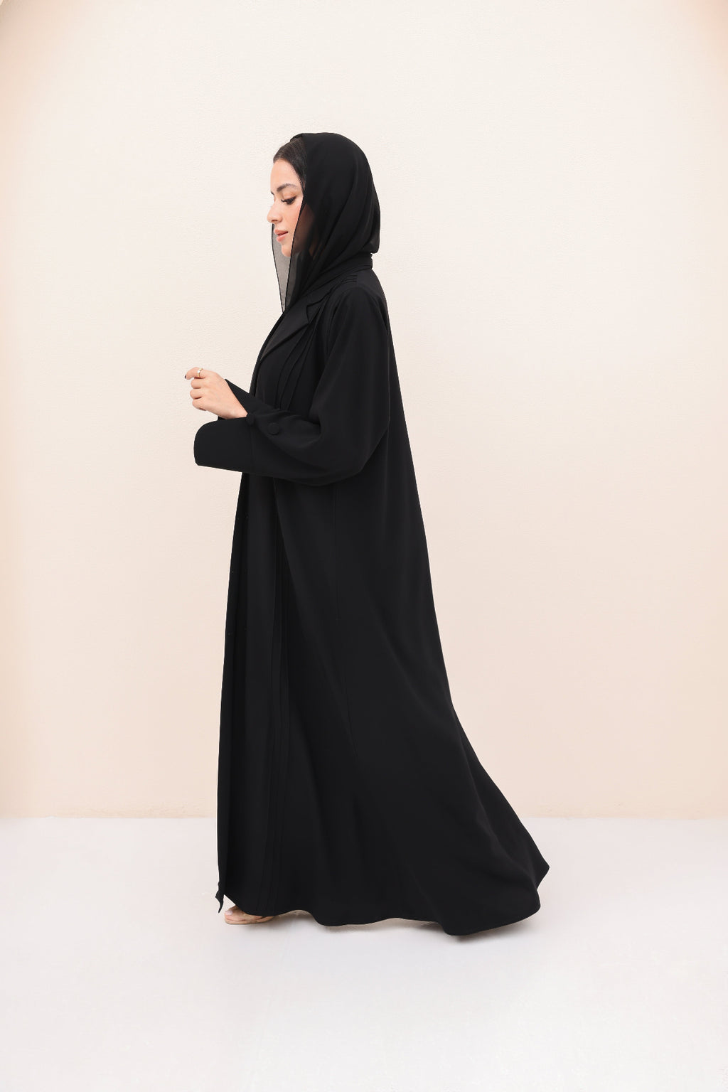Woman wearing a black abaya on a beige background