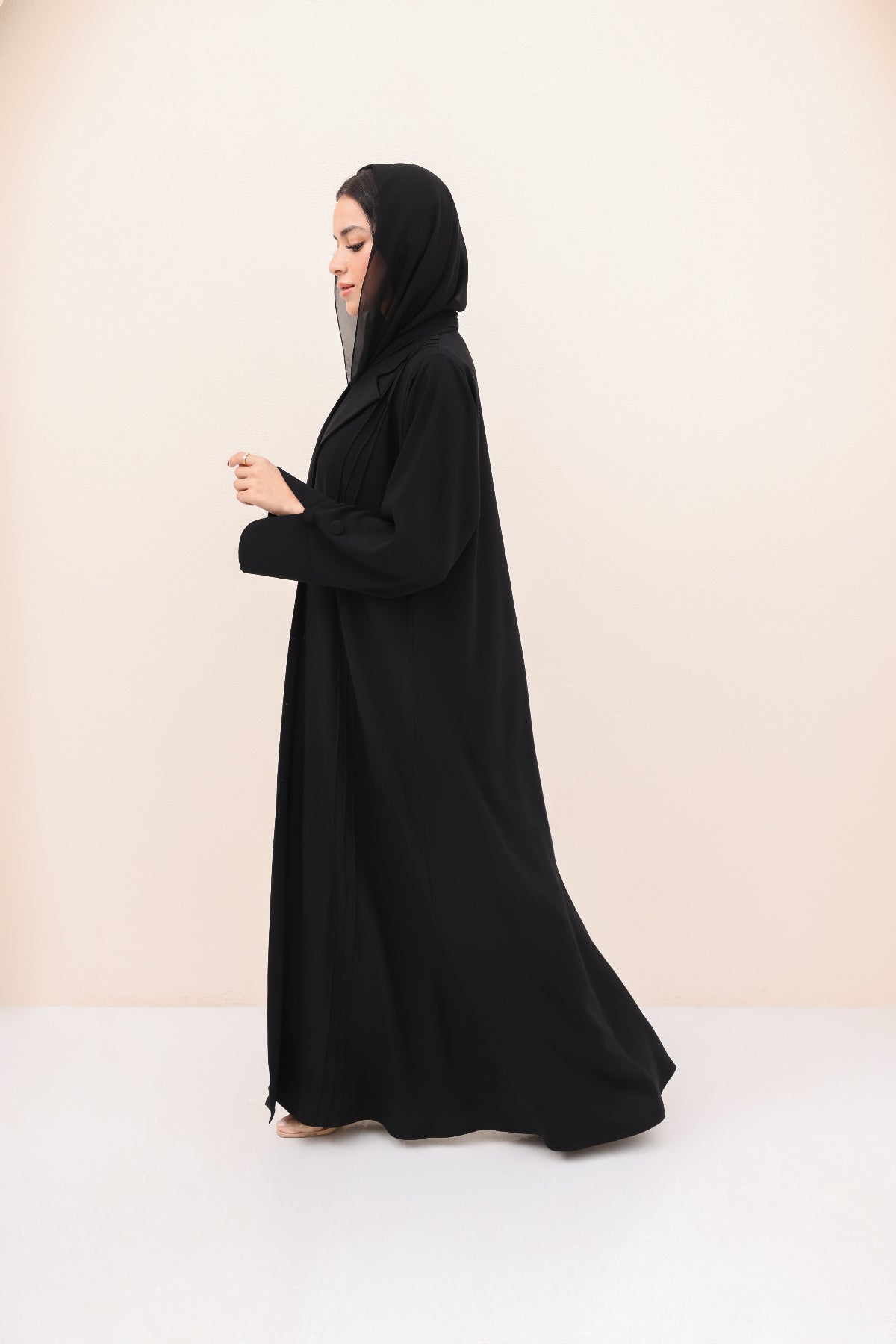 Woman wearing a black abaya on a beige background