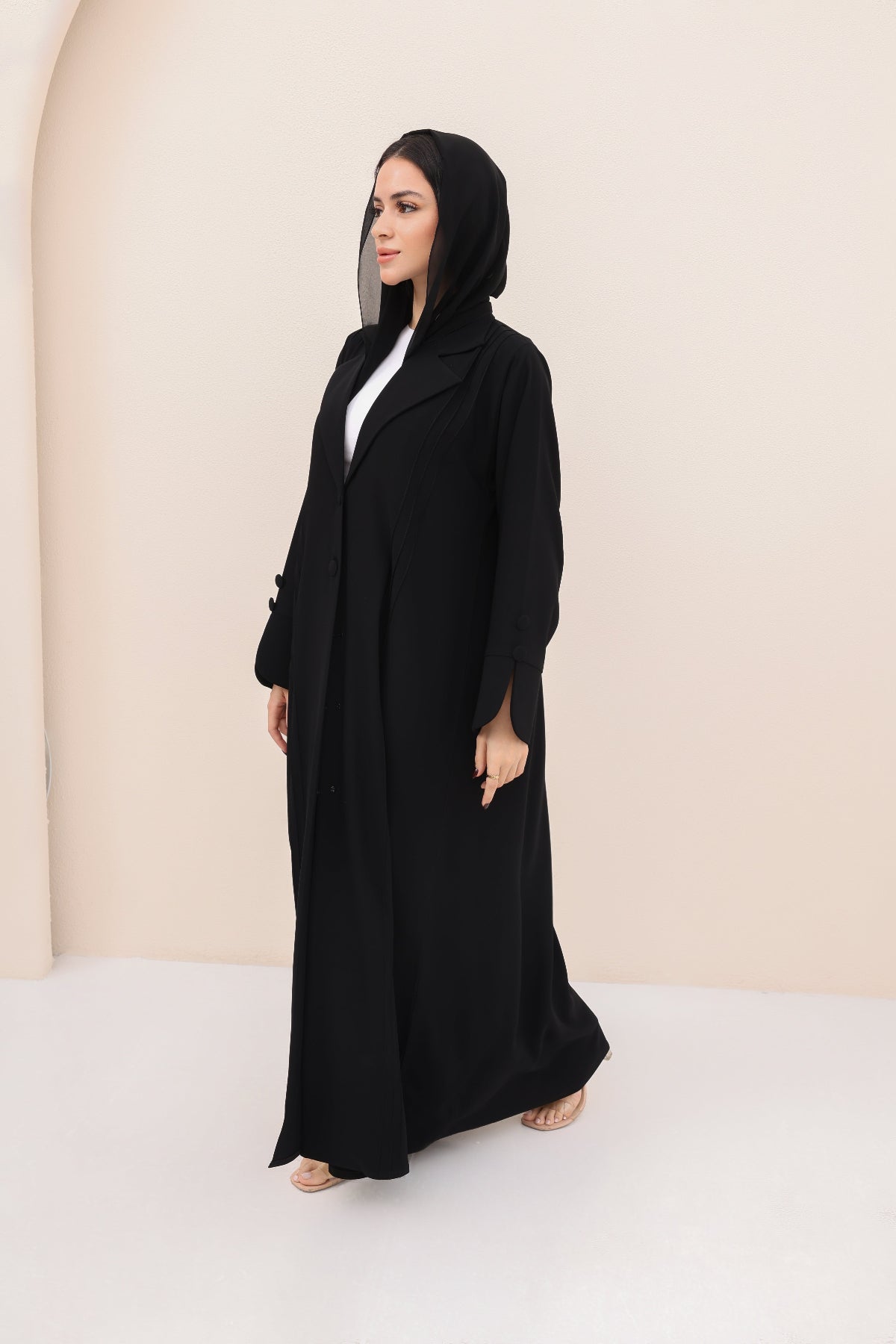 Woman wearing a black abaya in a minimalistic setting