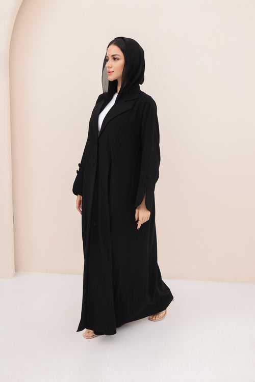 Woman wearing a black abaya in a minimalistic setting