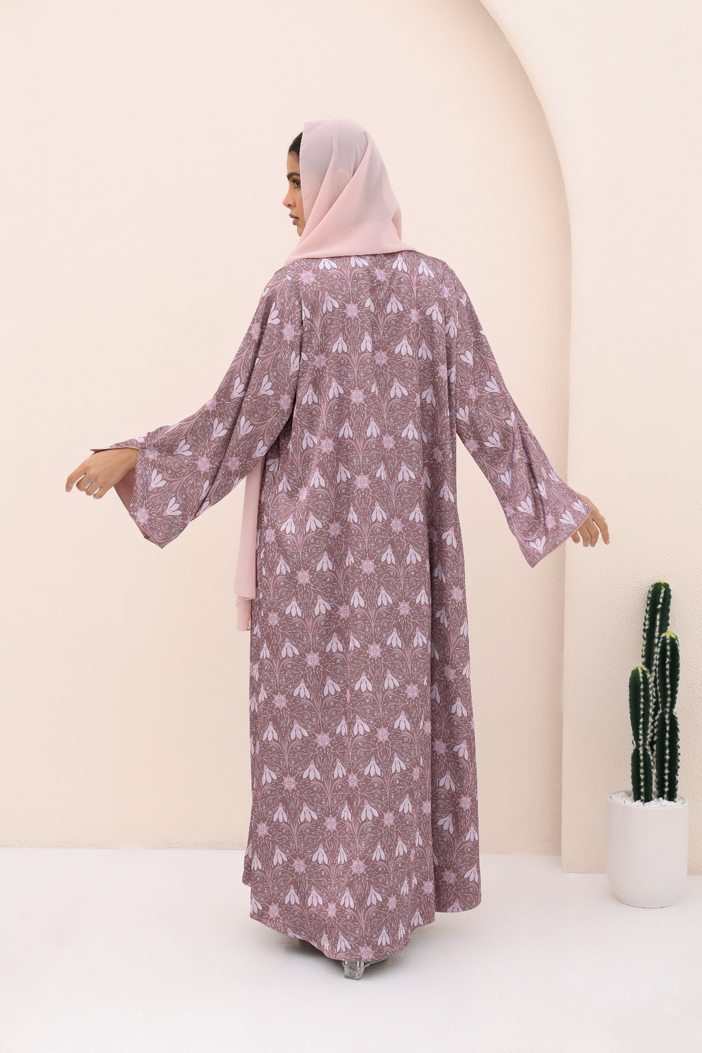 Woman wearing a patterned dress with a hijab in a minimalistic setting