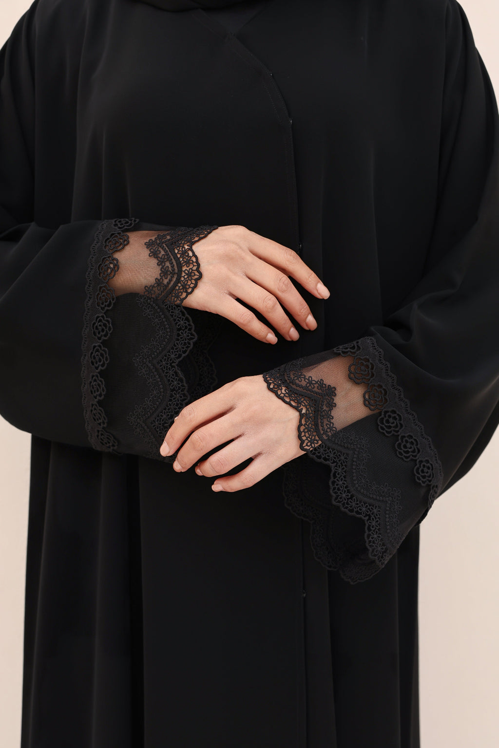Black abaya with lace cuffs on a beige background