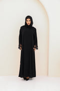 Woman wearing a black abaya against a white background