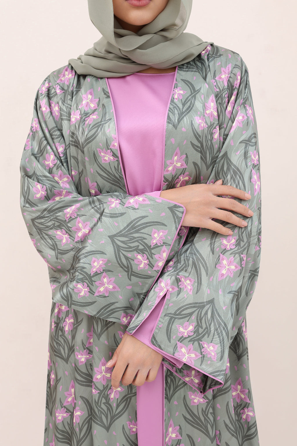 Woman wearing a gray floral abaya with pink accents on a beige background