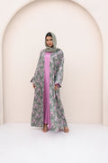 Woman wearing a floral abaya with a pink inner garment against a neutral background